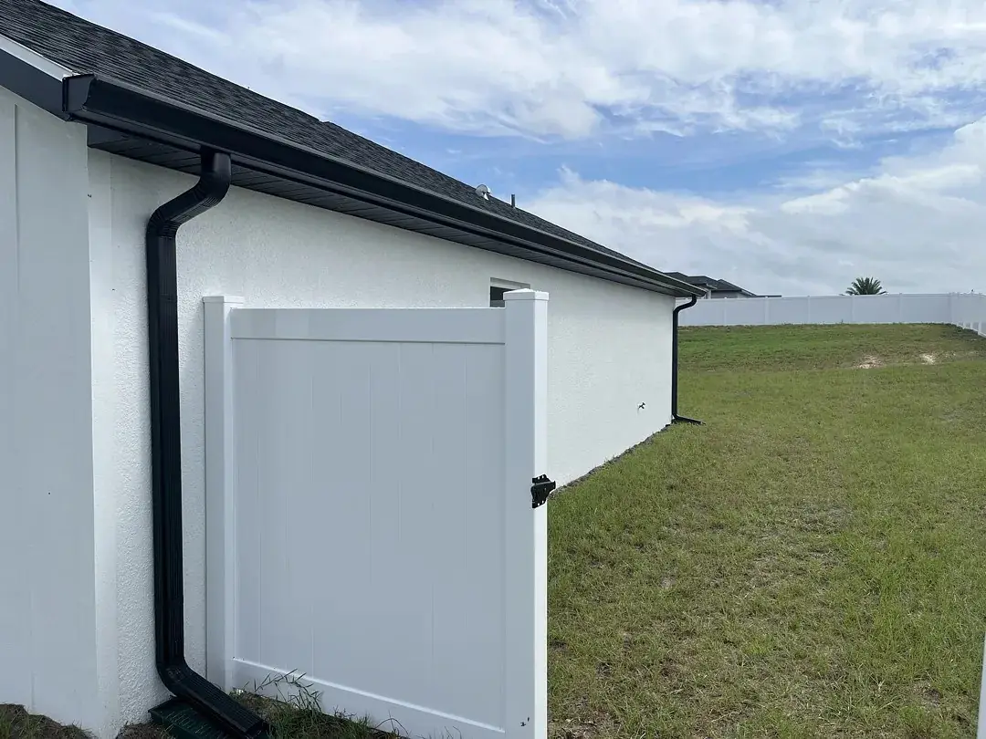 Black seamless gutter and downspout on a white stucco wall