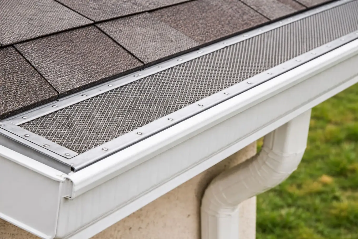 Mesh gutter guard on a white gutter with a downspout