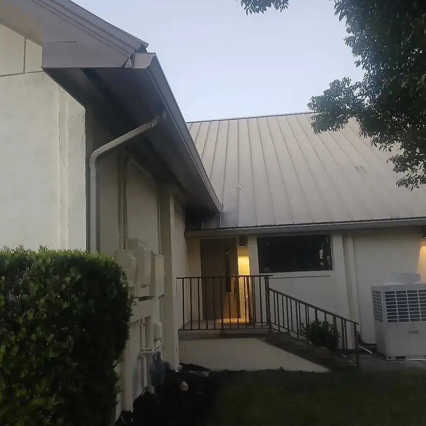 White gutters and downspout on a home with a metal roof