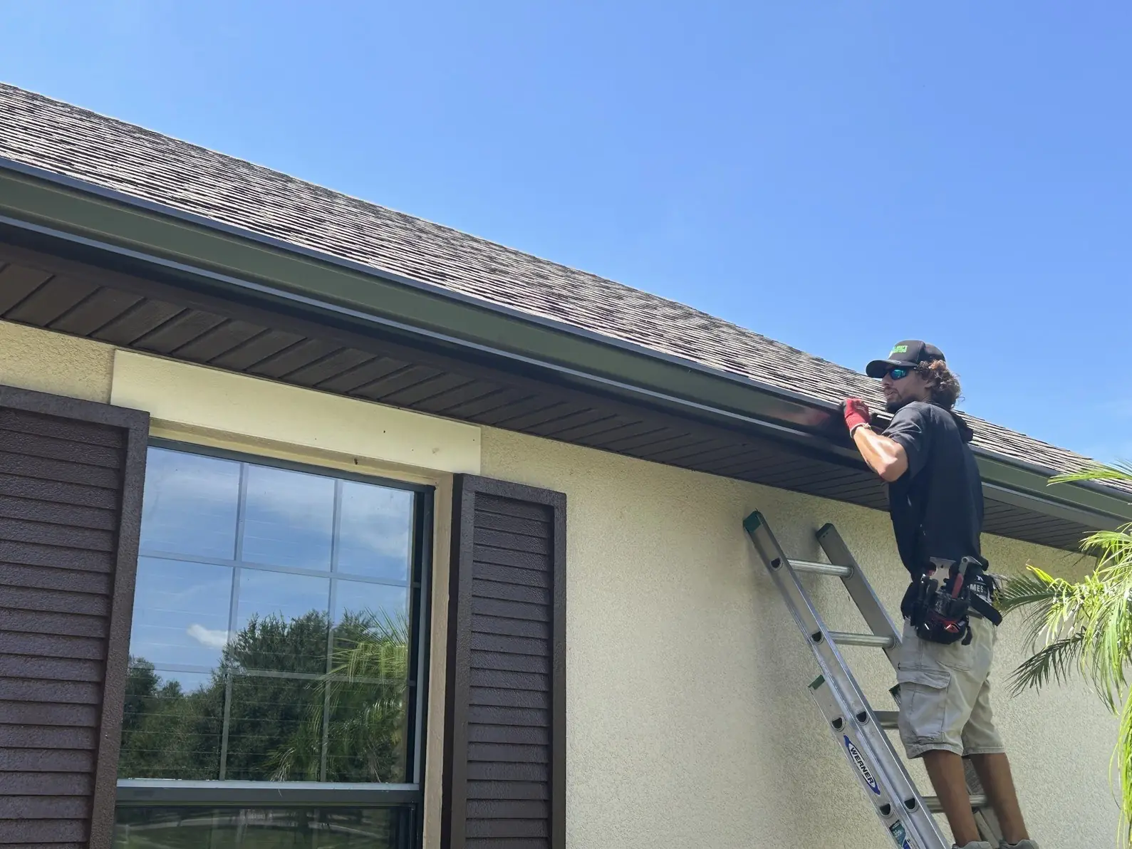 Larry's Gutters installer on a ladder fastening a seamless gutter to the fascia