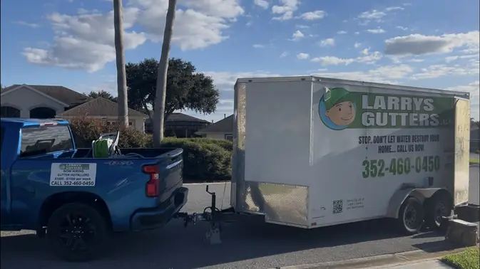 Larry's Gutters truck and gutter trailer parked at a job