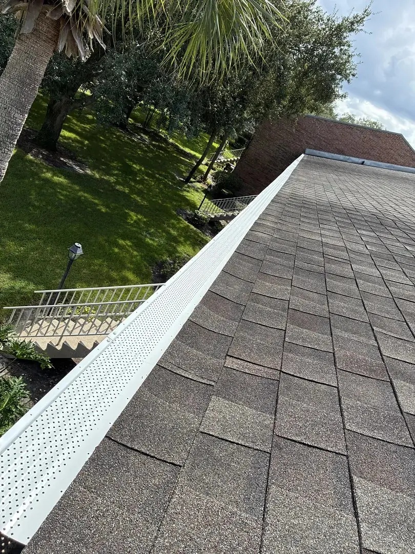 White gutter guard installed along a shingle roof