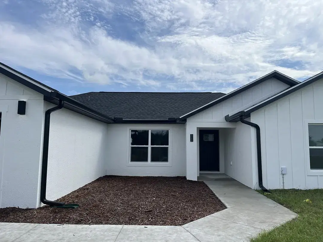 White home with black seamless gutters and downspouts at each corner