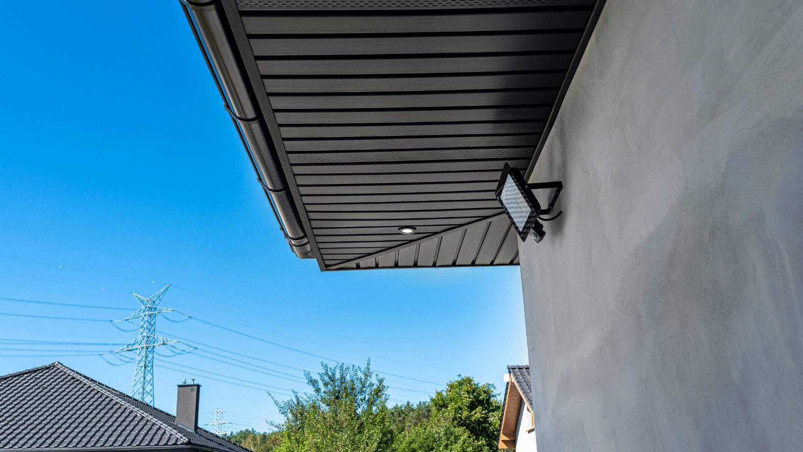 Black gutter and soffit with a floodlight on a white house
