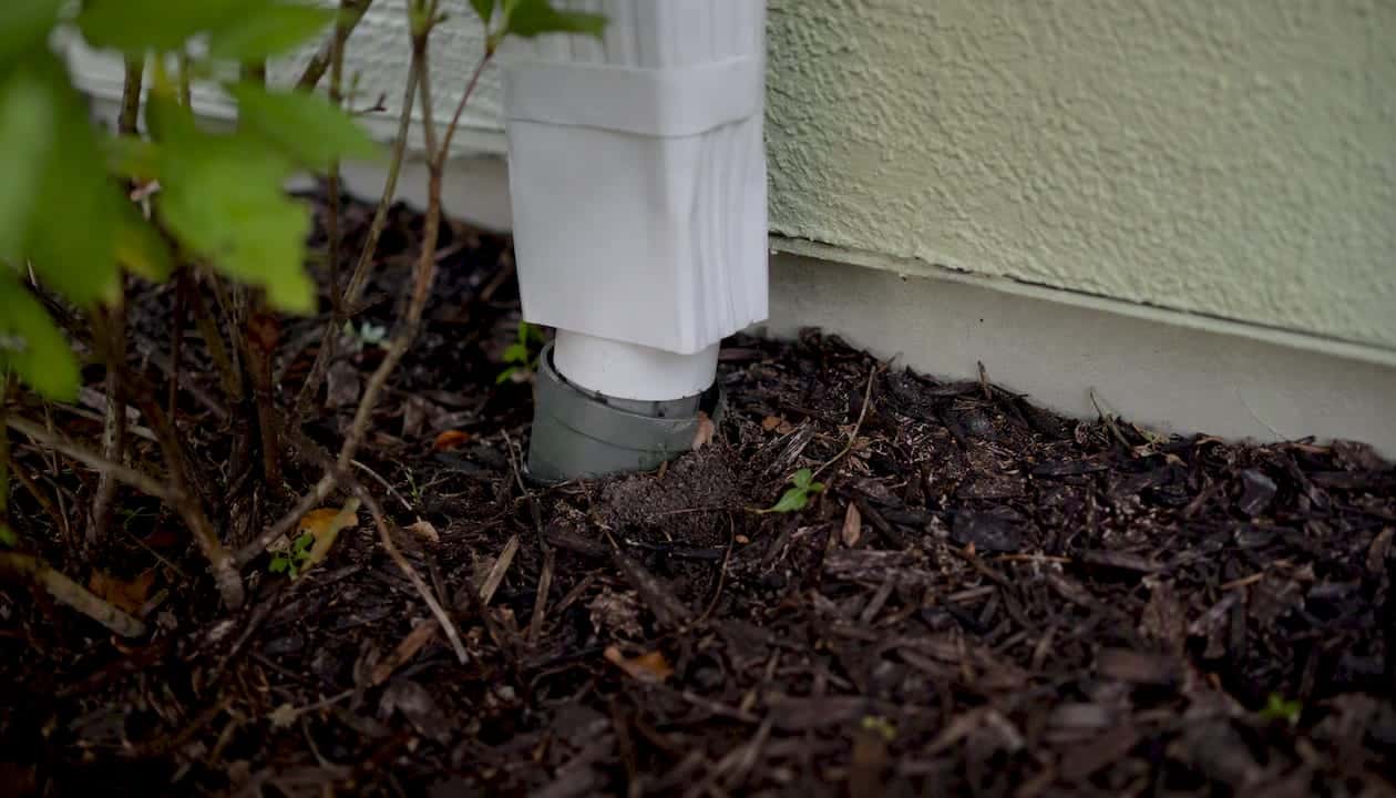Downspout adapter joint partially covered by mulch