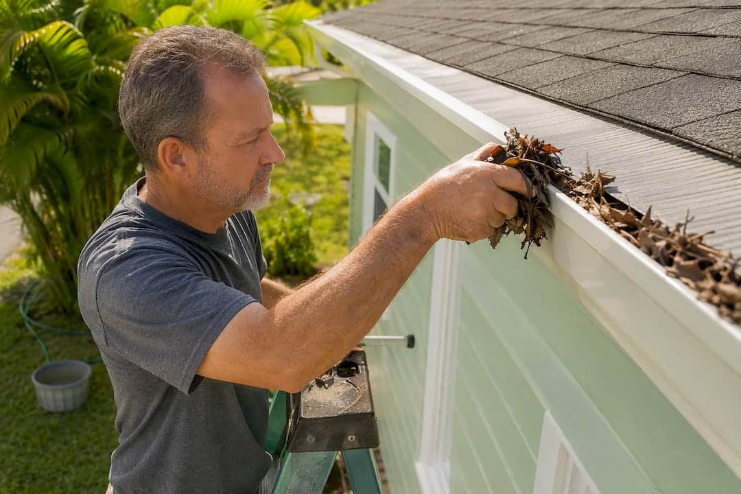 Homeowner clearing debris from gutter