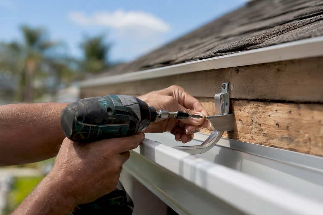 Close-up of hands installing hidden gutter hanger