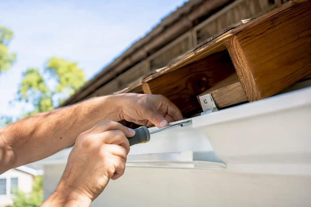 Hands clipping hidden gutter hanger into aluminum gutter
