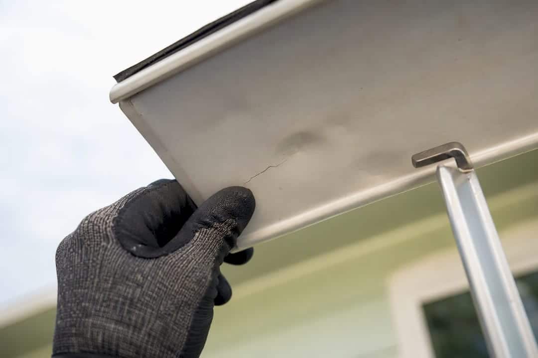 Close-up inspection of gutter crack and hail dent